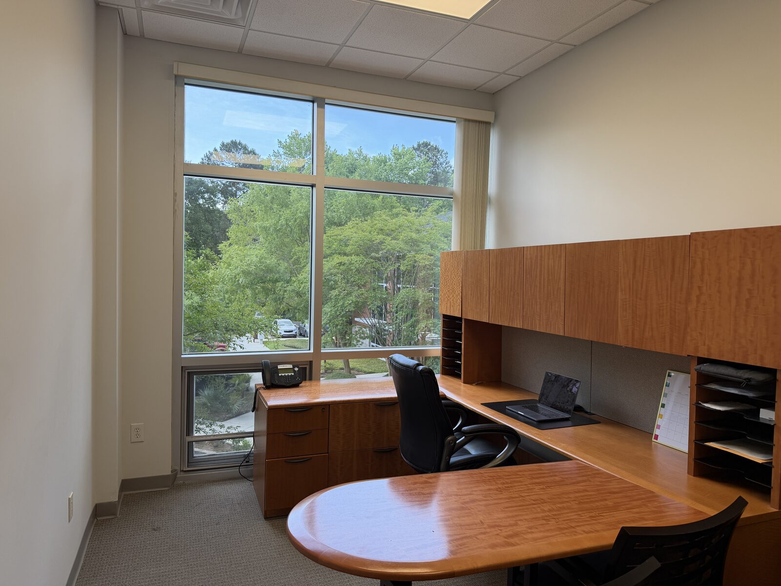 Furnished private executive office with built-in wood desk and windows